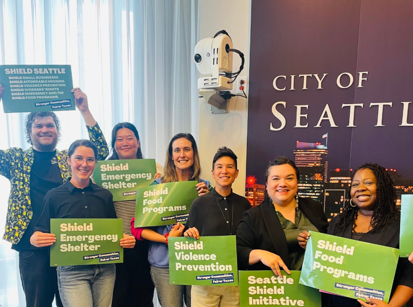 a group of human service workers hold up signs supporting the shield intiative