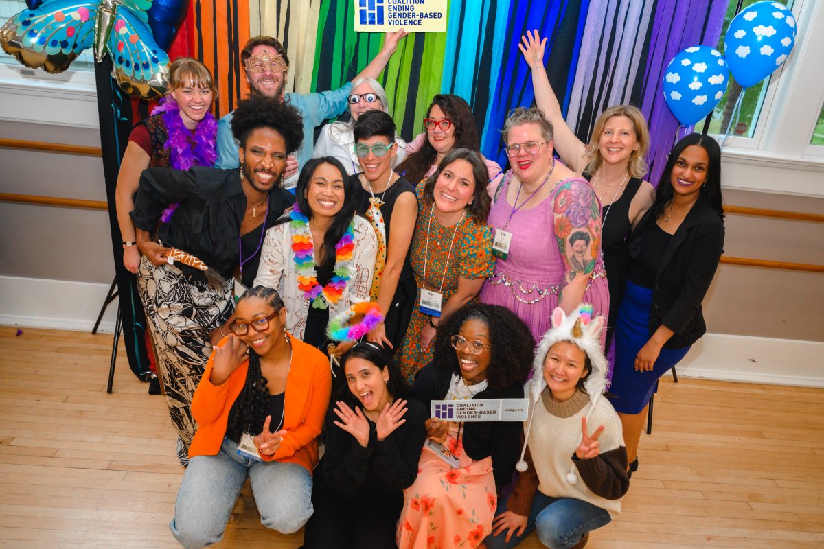 a group of people dressed in costume props smile and stand in front of a rainbow backdrop