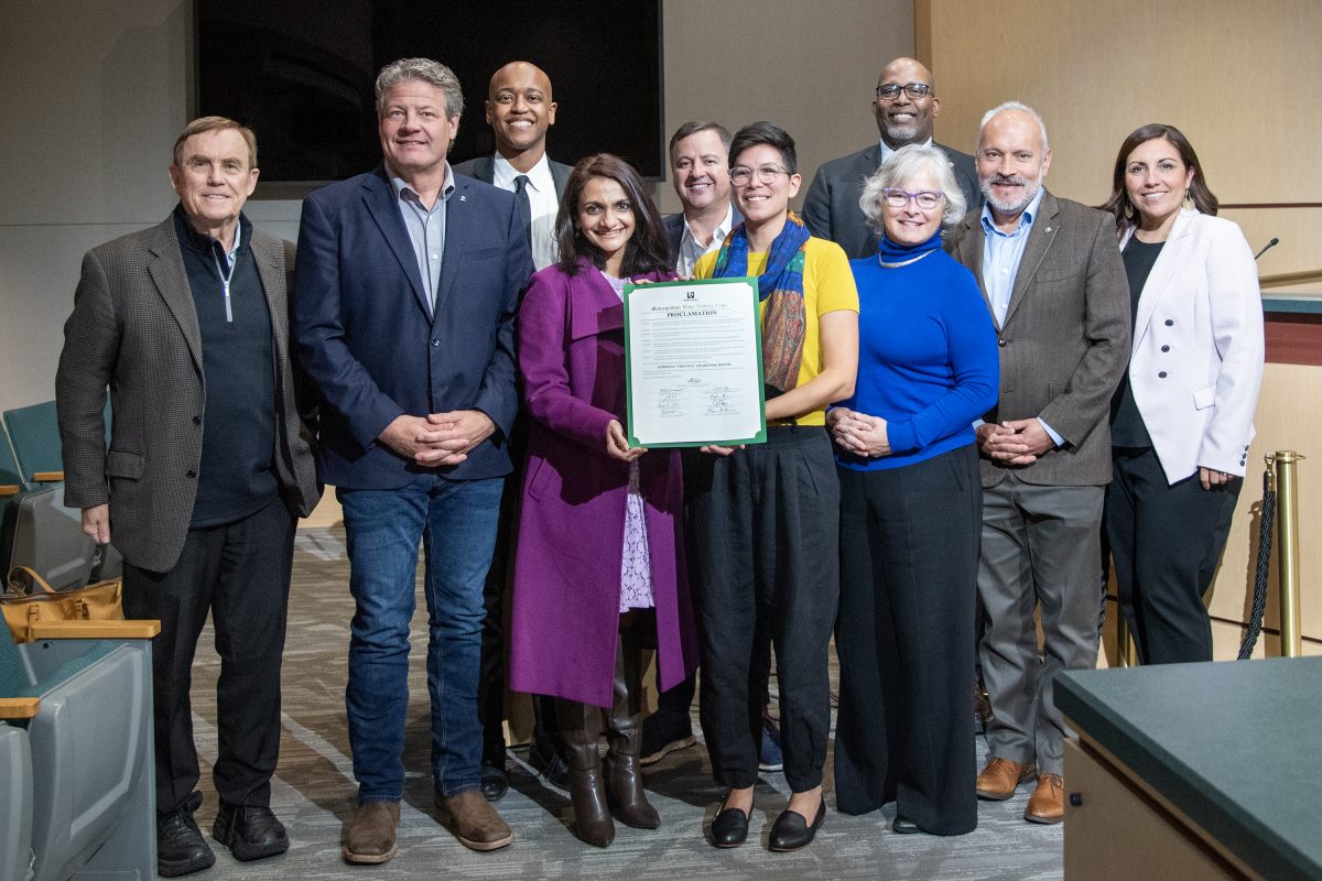 a group of people including King County Councilmembers stand smiling and holding up a letter stating october is domestic violence awareness month